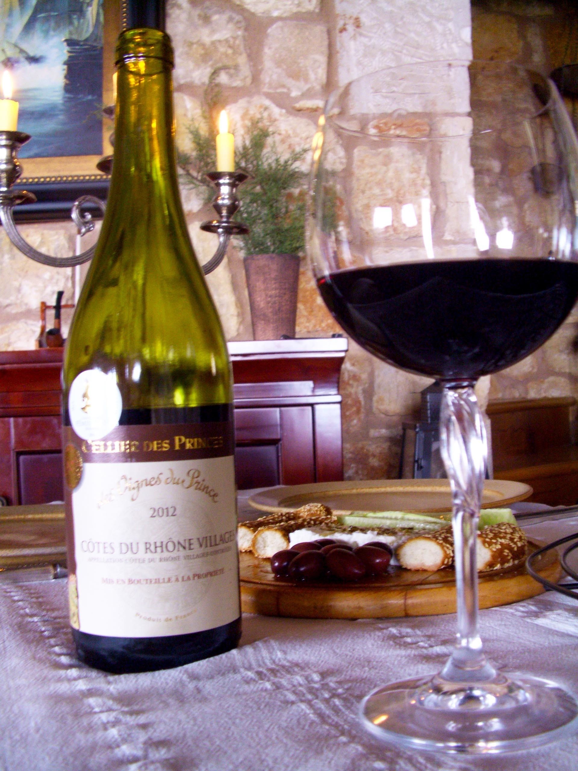 A bottle of wine and a glass of red wine on a table.