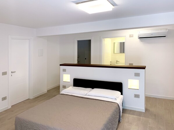 Une chambre à coucher avec un lit, un miroir et un appareil de climatisation.