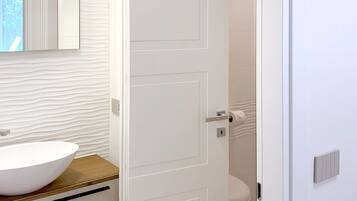 A bathroom with a white sink, a mirror, and a toilet.