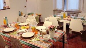 A dining area with a striped tablecloth, multiple chairs, and a variety of dishes and drinks. - B&B Villa Paradiso (Urbino)