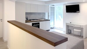 A modern kitchen with white cabinets, a wooden countertop, and a built-in dishwasher. - B&B Villa Paradiso (Urbino)