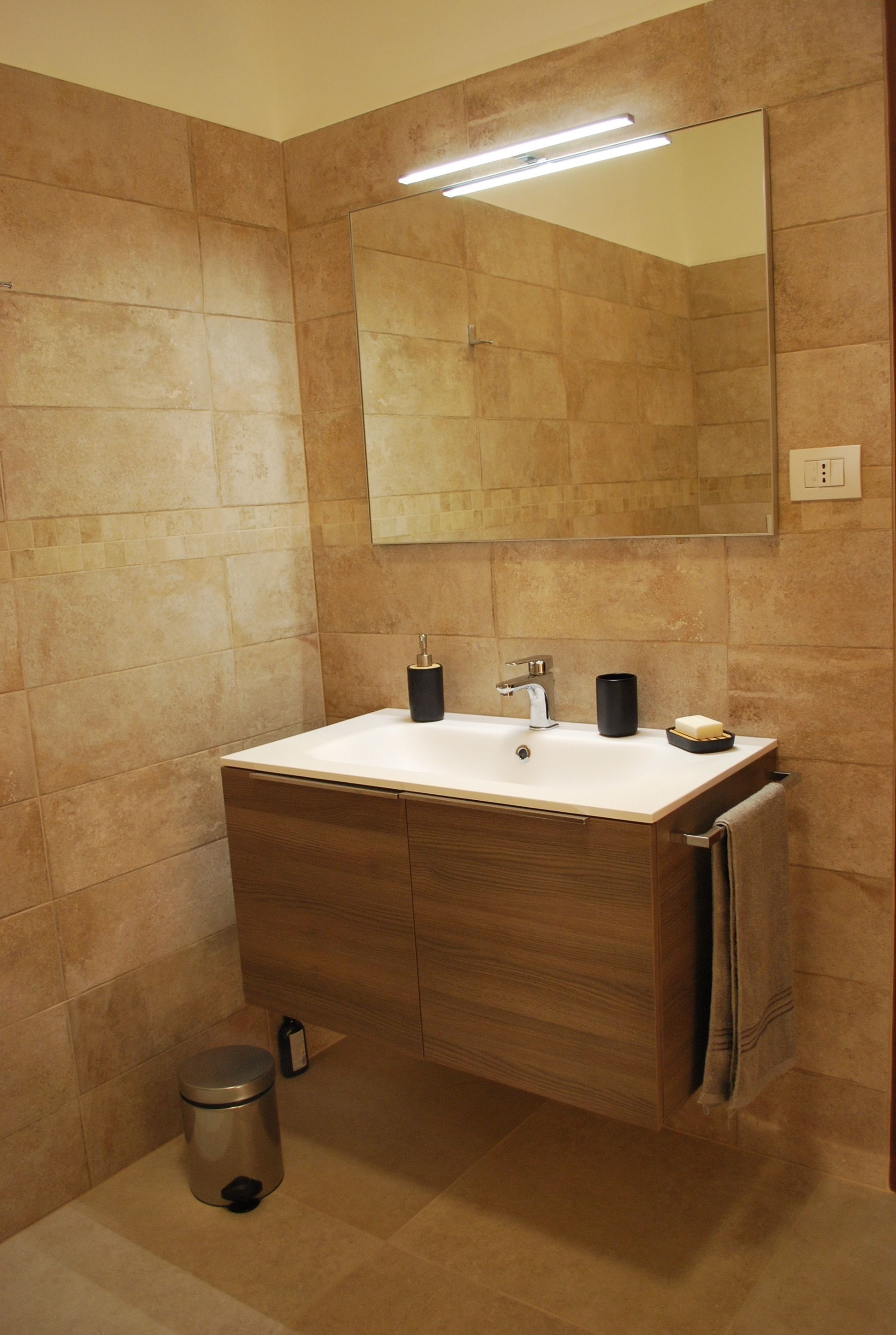 Une salle de bain moderne avec un lavabo blanc, un meuble-lavabo en bois et un grand miroir.