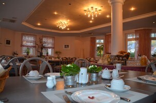 A dining area with tables set for breakfast, including plates, cups, and pitchers.
