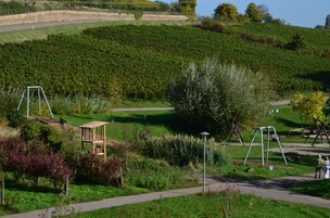 A park with walking paths, swings, and a small wooden structure.