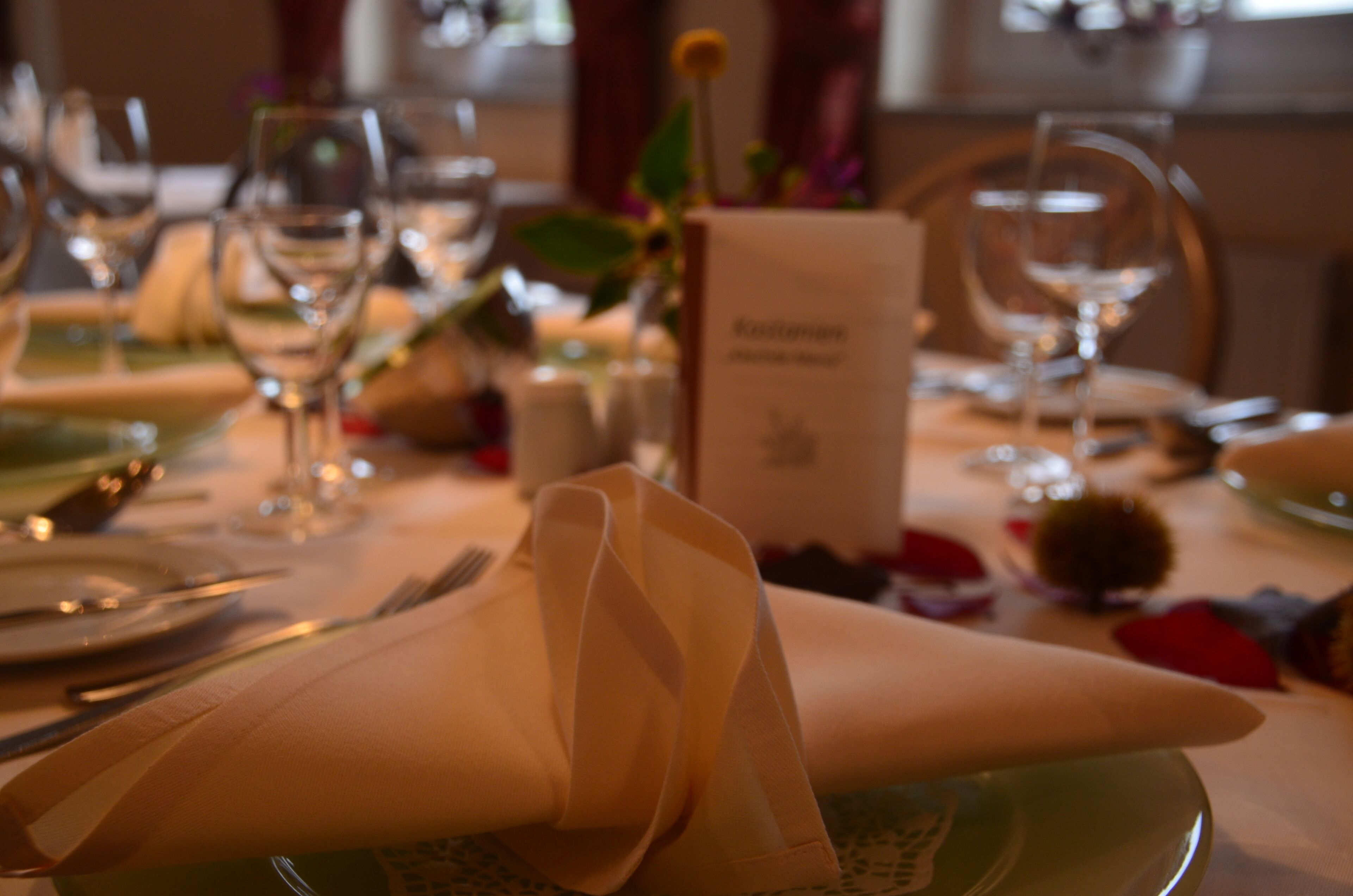 A dining table set with plates, cutlery, and wine glasses.