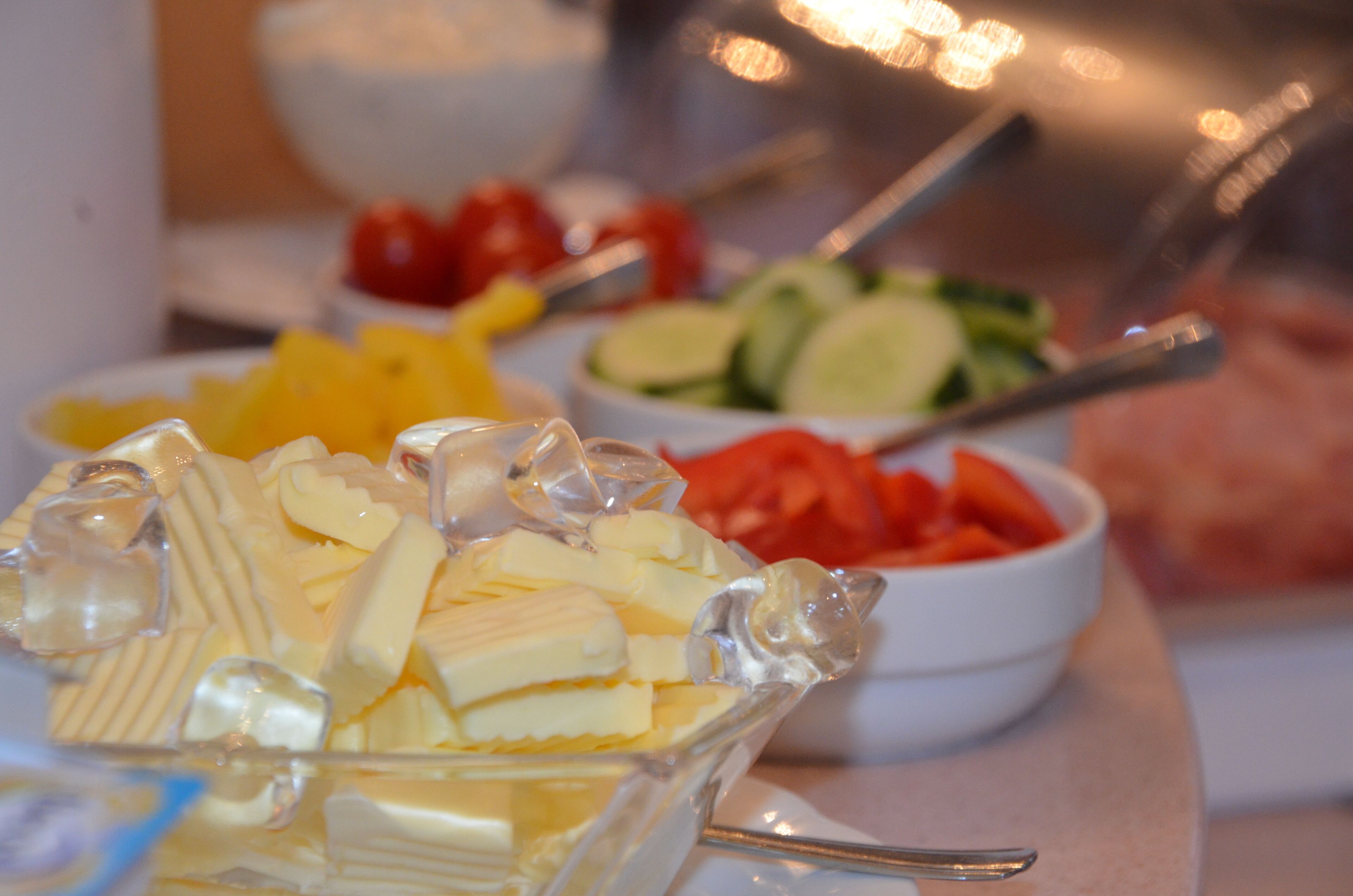 A buffet table with various food items including cheese, fruits, and vegetables.