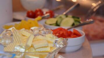 A buffet table with various food items including cheese, fruits, and vegetables.