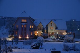 A hotel with multiple buildings, snow-covered surroundings, and illuminated windows.