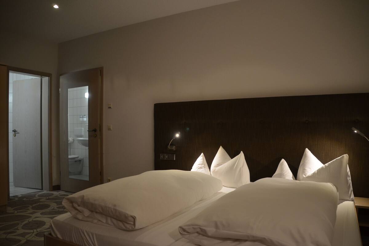 Ein Hotelzimmer mit einem großen Bett, einem Holzkopfteil und einem Nachttisch mit Lampe.