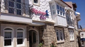 Ein Gebäude mit einer Stein-Fassade, weißen Fensterrahmen und einem Balkon mit schwarzen schmiedeeisernen Geländern.