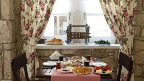 A dining table set with various dishes and drinks, a wooden rack, and floral curtains.