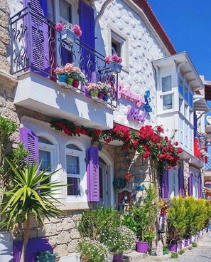Un edificio colorato con balconi decorati da fiori e persiane viola.