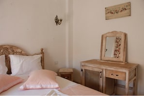 A bedroom with a wooden bed, a bedside table, a dresser with a mirror, and a floral wall decoration. - Alacati Ciftekuyu Butik Otel (Cesme)