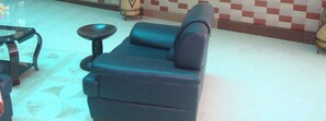 A dark blue sofa with a matching armrest and a small round table beside it. - Pearl Highway Hotel (Kampala)