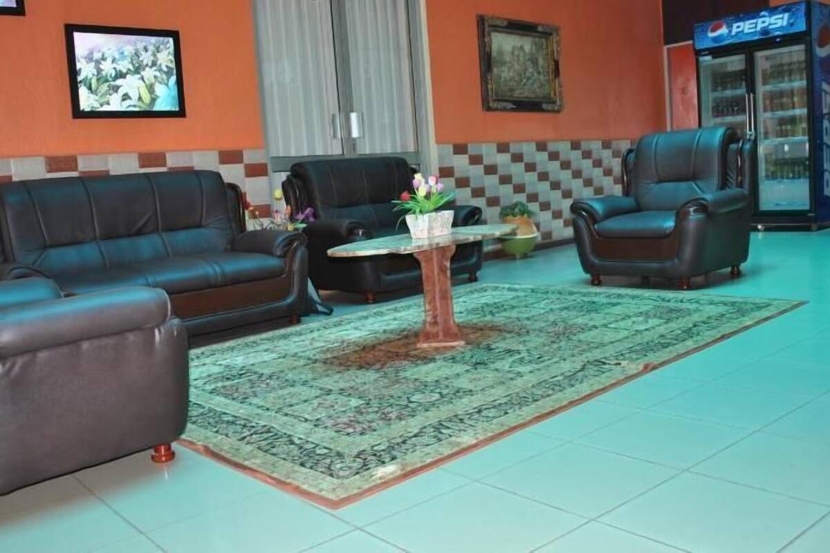 A lobby with a checkered wall, a coffee table with a plant, and two leather sofas.