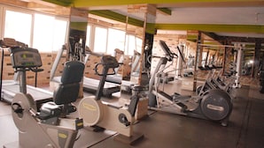 A gym with various exercise machines, large windows, and a brick wall. - Seb Hotel (Kampala)