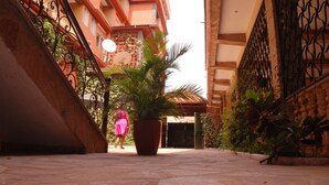 A courtyard with a potted palm tree, a staircase, and a building with balconies. - Seb Hotel (Kampala)