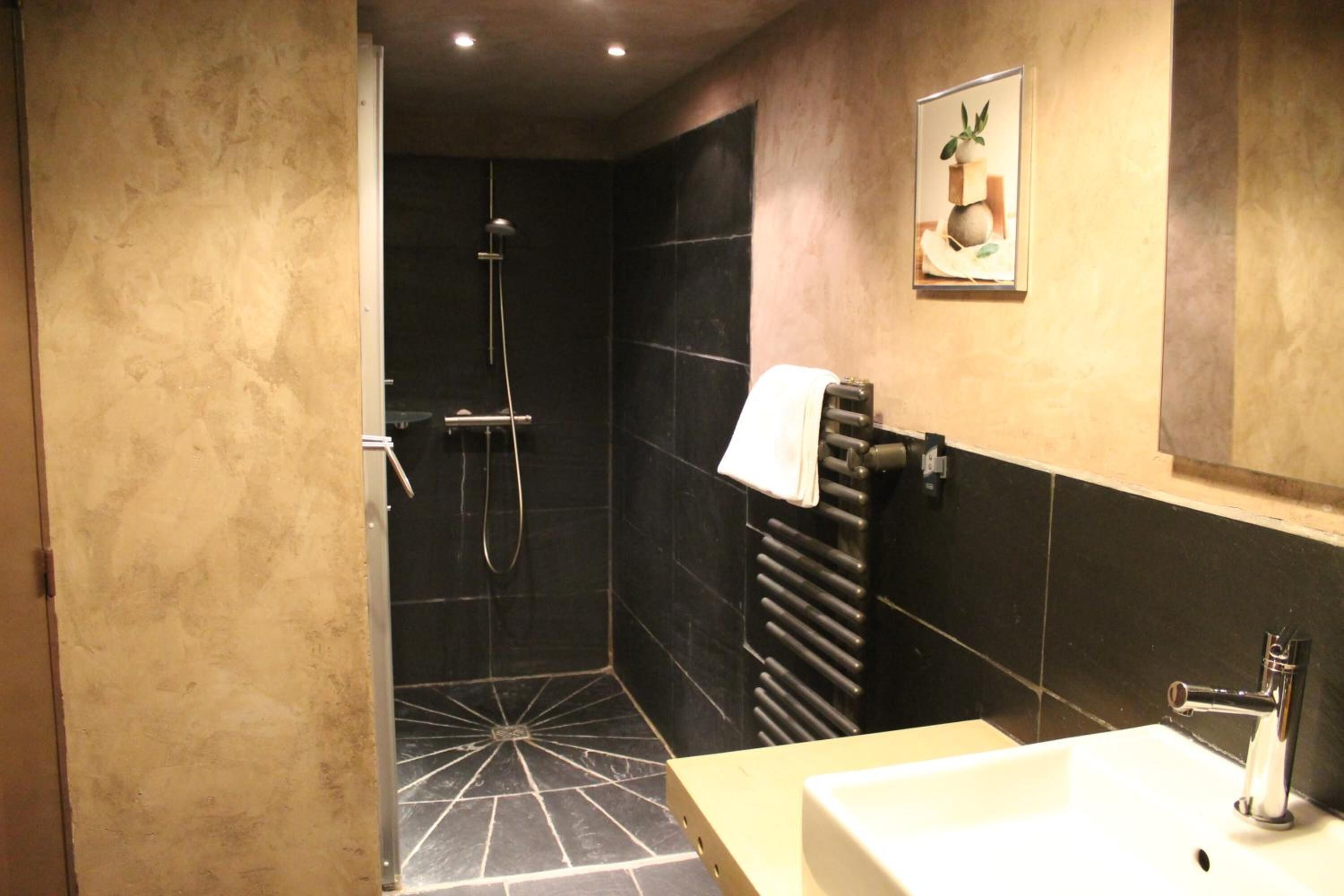 Un baño moderno con ducha, lavamanos y toallero.
