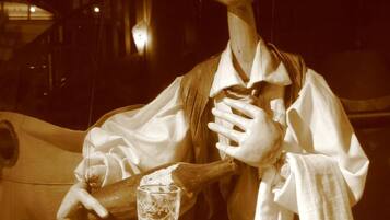 A puppet with a plate, a glass, and a napkin on a table.