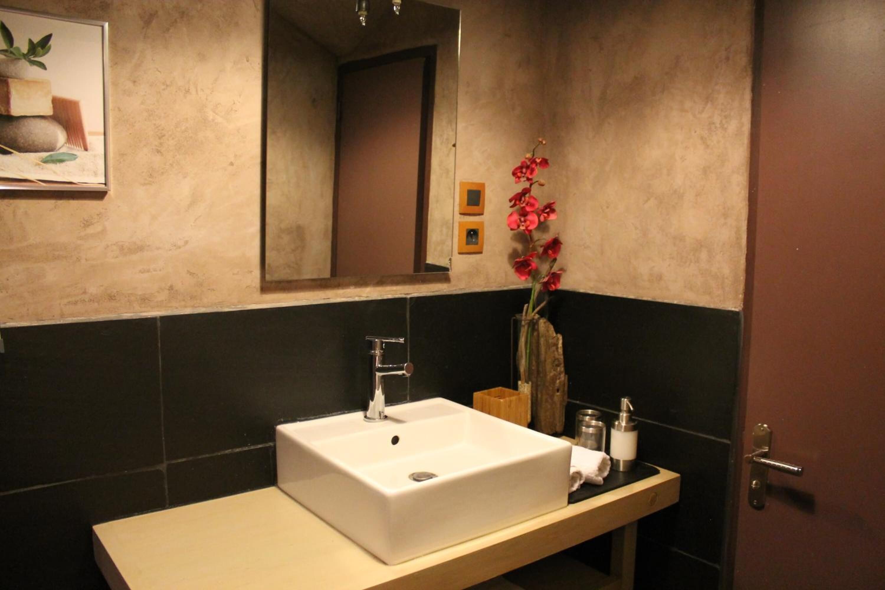 Une salle de bain avec un lavabo blanc, un miroir et un meuble-lavabo en bois.