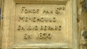 A stone plaque with the inscription "FONDE PAR ST MENEHOULD ENIGIO REPARÉ EN 1850".