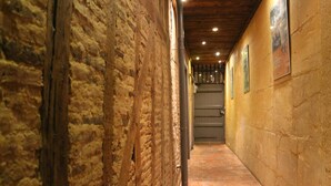 A narrow hallway with exposed brick walls and a tiled floor, leading to a door at the end. - Côté Chambres (Charleville-Mezieres)