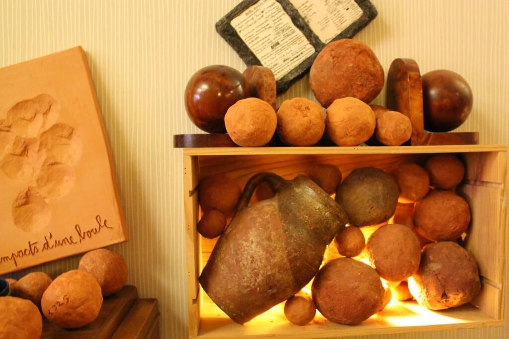 A wooden box filled with round, brown objects and a metal pitcher.