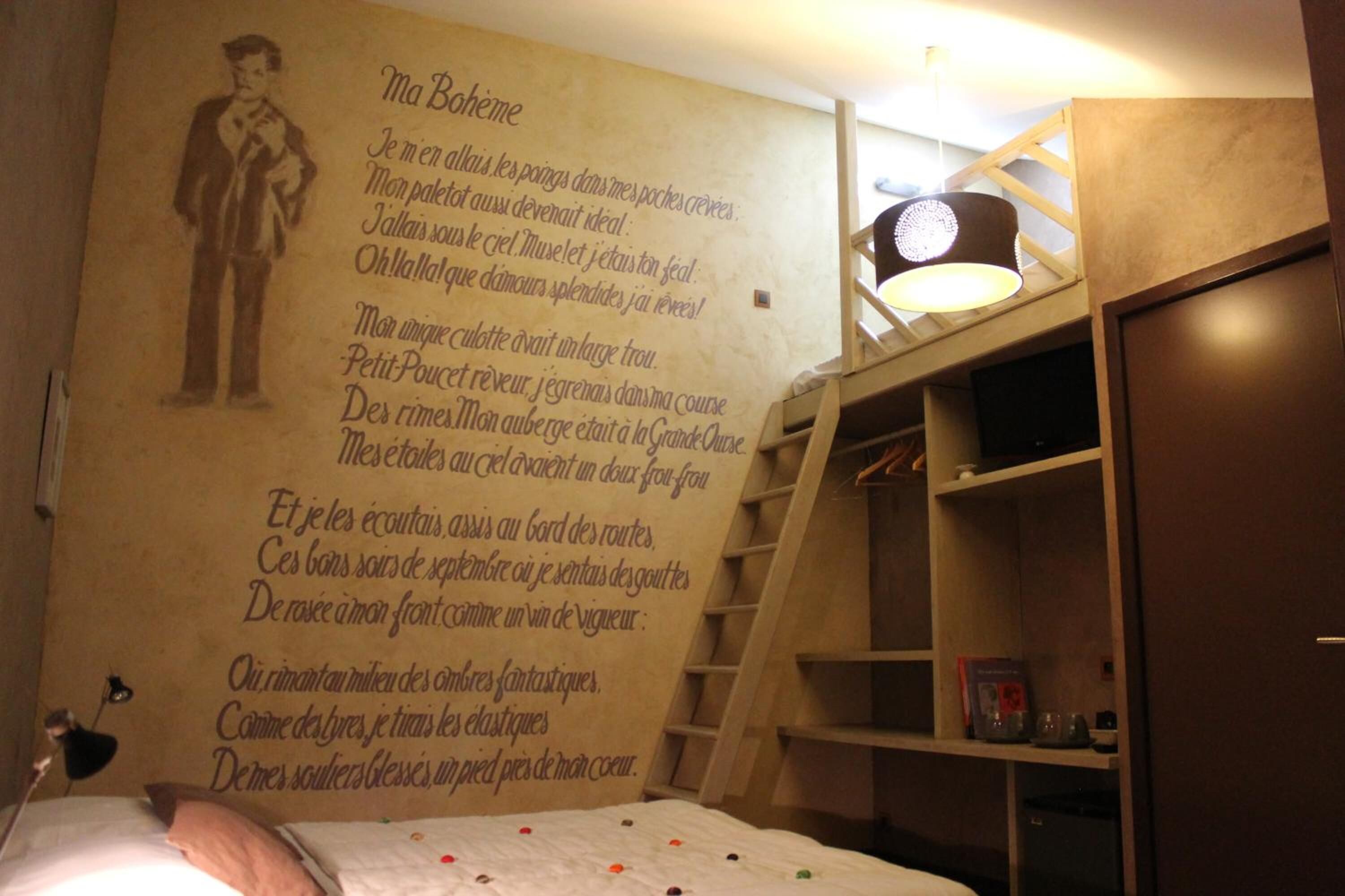 A bedroom with a large bed, a wall with a poem, and a ladder leading to a loft area.