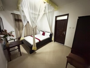 A bedroom with a bed, a chair, a desk, and a wardrobe.