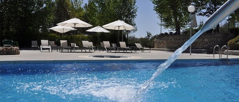Una piscina al aire libre de temporada, sombrillas