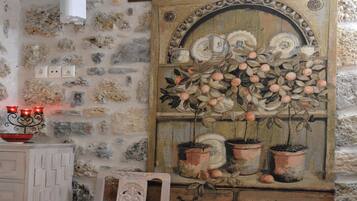 A rustic stone wall with a wooden cabinet and a decorative painting of fruit trees.