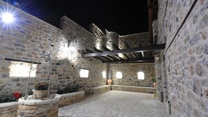 Une cour pavée de pierres, agrémentée d’une pergola, de murs en pierre et de plantes en pot.