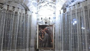 Une pièce aux murs de pierre, ornée d’un tableau encadré et de rideaux légers.