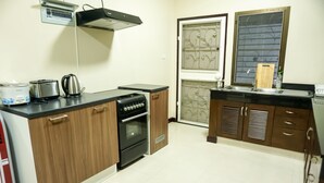 A kitchen with wooden cabinets, a black stove, a toaster, and a kettle. - Family Villa Iona with Private Pool (Si Sunthon)
