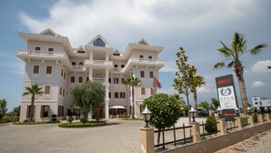 Un gran hotel de varios pisos con fachada simétrica, balcones y una bandera.