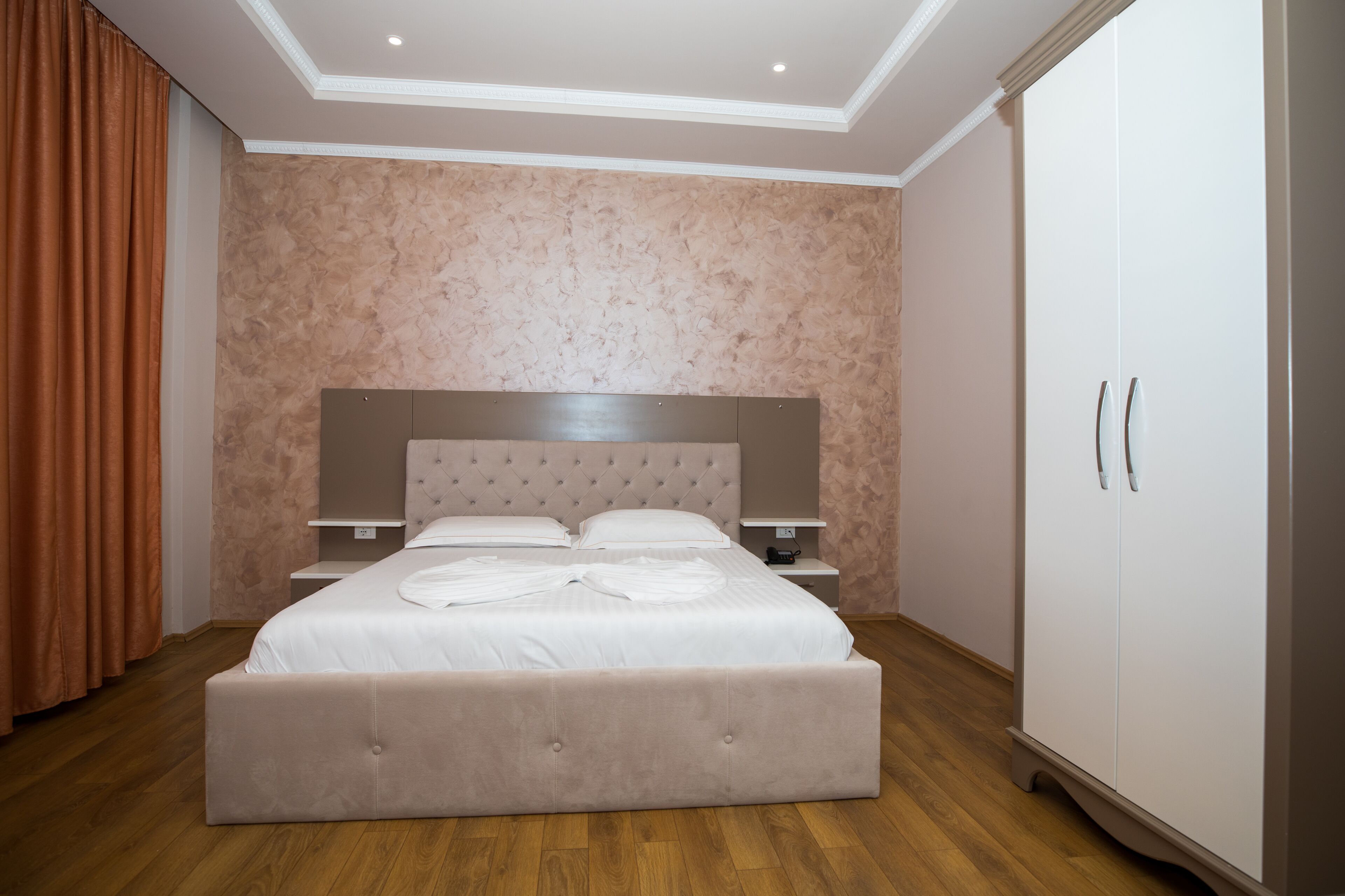 Un dormitorio con una cama grande, un armario, una mesita de noche e iluminación en el techo.