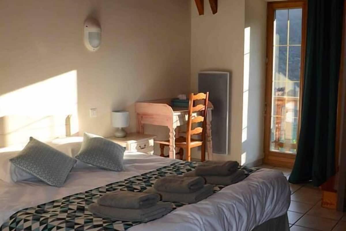 Un dormitorio con una cama grande, un escritorio y una silla.