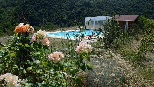 A pool area with a house in the background, surrounded by greenery and hills. - Chambres Et Tables D'Hote De Margaridou (Blesle)