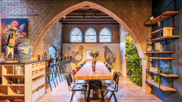 A dining area with a long wooden table, black chairs, and a brick archway. - Bunk Hotel Amsterdam (Amsterdam)