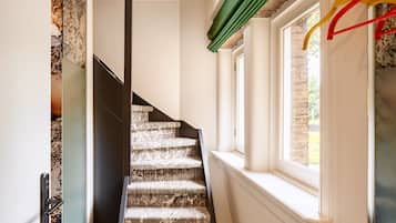 Eine Treppe mit einem gemusterten Teppich, eine Tür mit Griff und ein Fenster mit Blick auf Grünflächen.