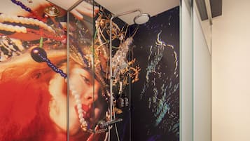 Una doccia con pareti divisorie in vetro e un grande murale colorato sulla parete.