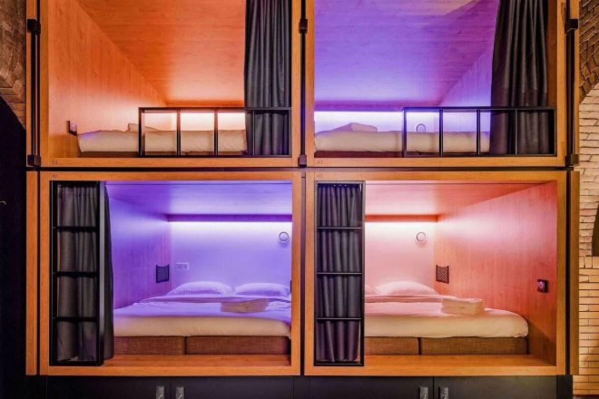 Una cabaña de cuatro habitaciones con literas, cada una con ventana y cortina.