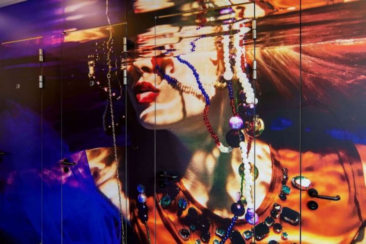 Una pared con una obra de arte grande y colorida que muestra a una persona adornada con joyas.