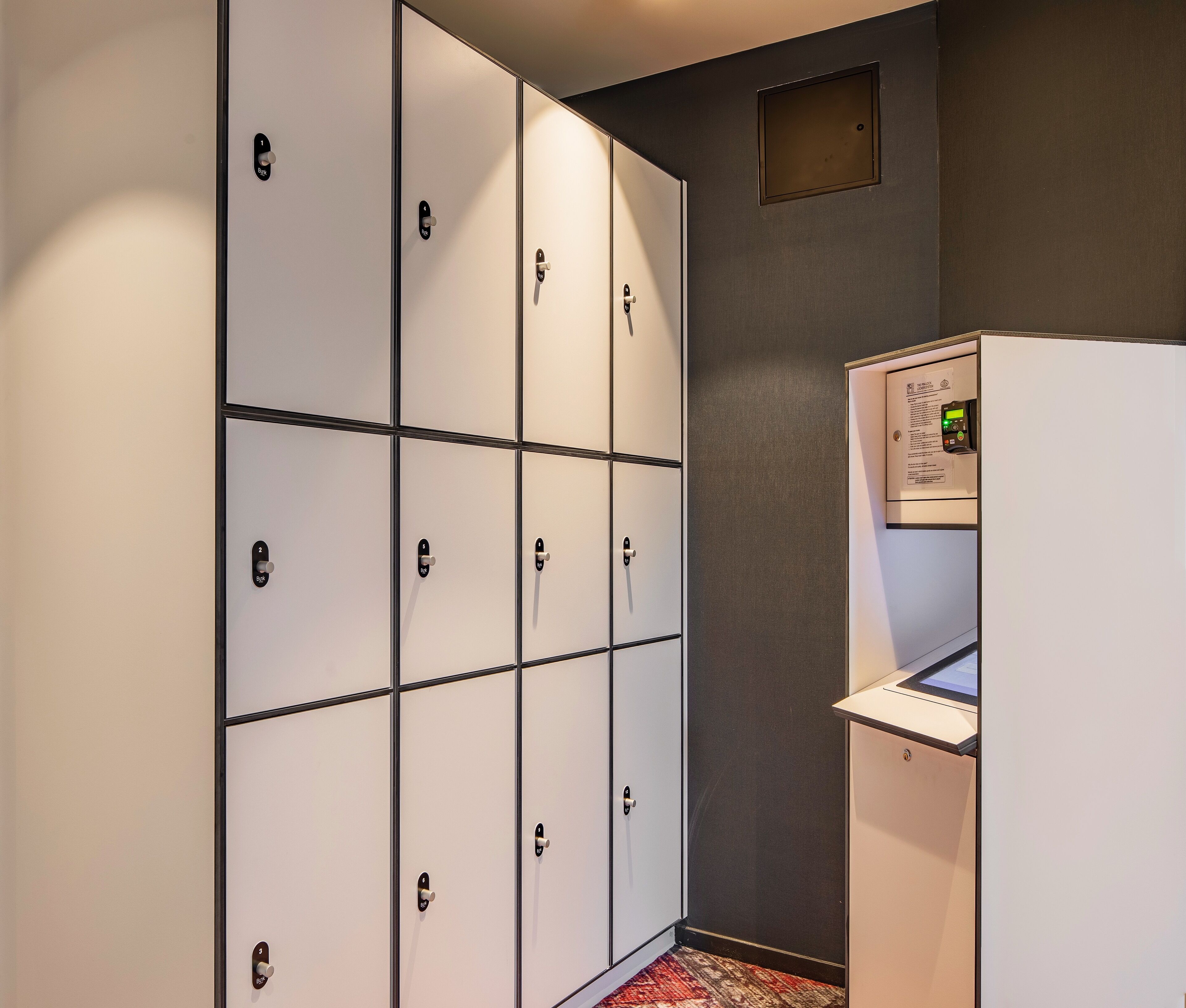 Une chambre d’hôtel avec un mini-bar, une petite fenêtre et une porte à clé.