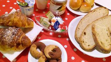 A table with various food items including pastries, bread, and a fruit bowl.