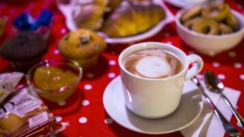 A table with a cup of coffee, a bowl of cookies, and a plate of pastries.