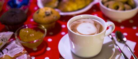 A table with a cup of coffee, a bowl of cookies, and a plate of pastries.