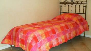 Un lit simple avec un cadre en métal et une couverture colorée.