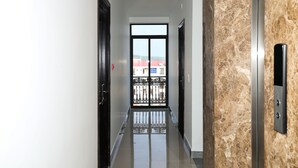 Un pasillo con vistas a un balcón, una puerta y una pared con superficie texturizada.