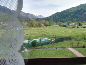 A view of a swimming pool surrounded by a fenced area with a mountain backdrop. - Hotel San Francisco Rural (Parres)